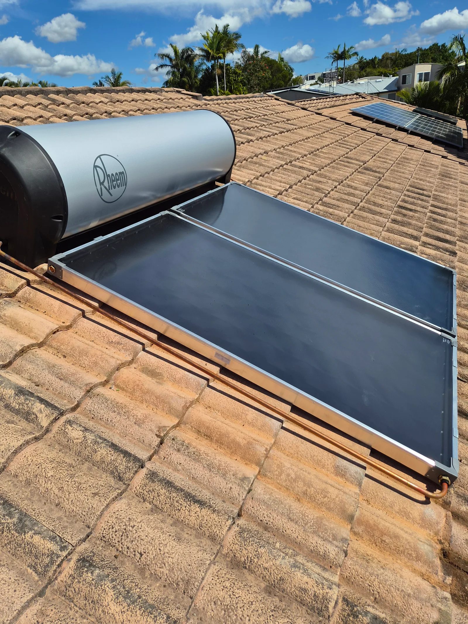 A Rheem solar hot water system installed by RCM on a tiled Sunshine Coast roof, collectors and tank in place